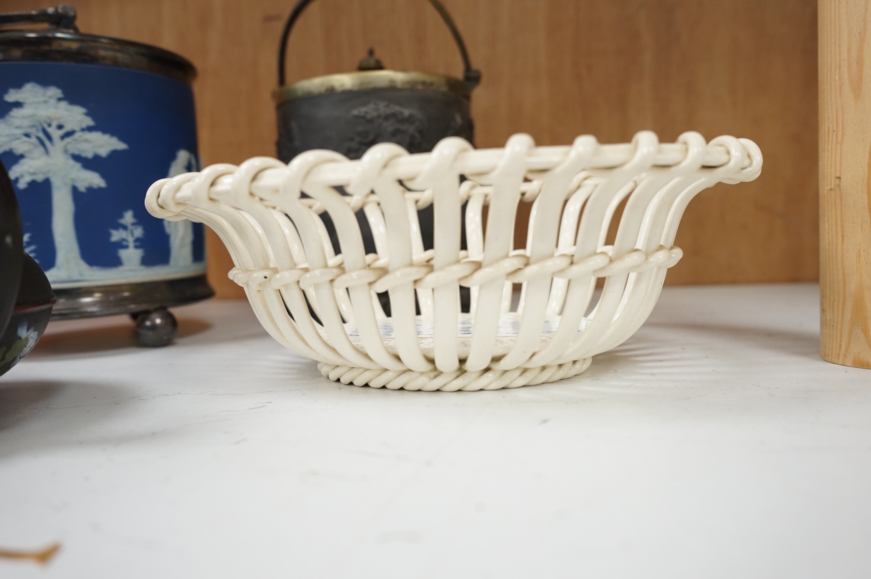 A collection of Wedgwood comprising basalt and jasper biscuit barrels, an enamelled basalt teapot, and a cover and creamware basket, largest 26cm high (4)